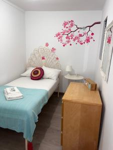 1 dormitorio con 1 cama y una rama con flores rosas en Apartamento com escada e pátio, em frente praia en Paço de Arcos