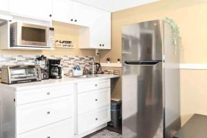 La cuisine est équipée d'un réfrigérateur en acier inoxydable et de placards blancs. dans l'établissement Registered Renovated walkout suite with King-bed, Kitchen, Parking, Patio, à Calgary