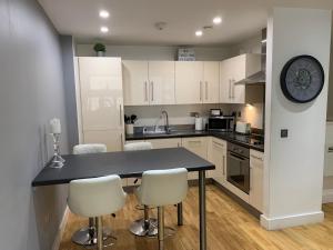 マンチェスターにある2 Bedroom Apartment - Close to Piccadilly Train Station / Edge of the Northern Quarterのキッチン(白いキャビネット、黒いカウンタートップ付)