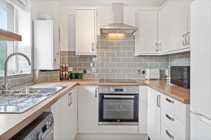 a kitchen with white cabinets and a sink at Beautiful 2 Bedroom Apartment MK Free Parking in Woolstone