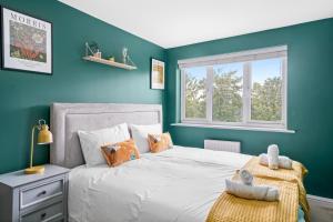 een slaapkamer met een bed met blauwe muren en een raam bij Beautiful 2 Bedroom Apartment MK Free Parking in Woolstone