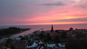 a sunset over a town with a church and the ocean at Reetferienhaus - Schaprode Hafen in Schaprode