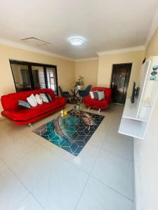 a living room with two red couches and a table at Thati @ C-rane Lodge in Phalaborwa
