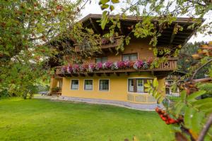 ein gelbes Haus mit einem Balkon mit Blumen darauf in der Unterkunft Gästehaus Hochkönig in Filzmoos