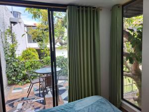 a bedroom with a bed and a balcony with a table at Jardines Ambato in Ambato