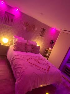 Un dormitorio con una cama con luces rosas. en Love room. Une bulle d évasion., en Lisses