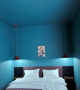 a blue bedroom with a bed with a blue wall at Green Rooms in Kutaisi