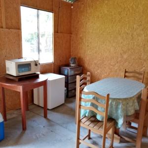 um pequeno quarto com uma mesa e um micro-ondas em Qintipillpi Lunahuaná em Lunahuaná