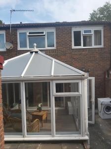 a white conservatory with a pitched roof at super comfortable 3 bed house in Houghton Regis