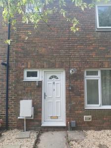 a brick house with a white door and two windows at super comfortable 3 bed house in Houghton Regis