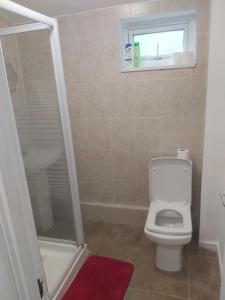 a bathroom with a toilet and a shower and a window at super comfortable 3 bed house in Houghton Regis