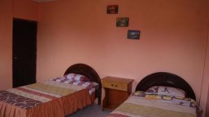 two beds in a bedroom with orange walls at Zumag Sisa in Tena