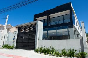 une maison moderne avec un garage noir dans l'établissement Ap Studio Praia Campeche, à Florianópolis