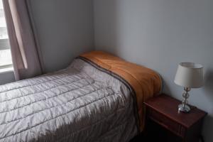a bedroom with a bed and a table with a lamp at Habitaciones en Departamento compartido centro de Viña in Viña del Mar