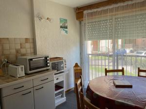 cocina con mesa, microondas y ventana en Appartement Clos du Bastan avec piscine, en Luz-Saint-Sauveur