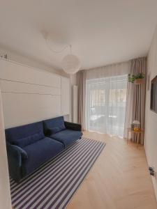 salon z niebieską kanapą przed oknem w obiekcie NØDA - Nørdic Design Apartment with Terrace w Liptowskim Mikulaszu