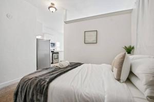 een witte slaapkamer met een bed en een koelkast bij Detached guesthouse in Belmont Heights in Long Beach