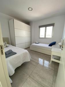 een witte slaapkamer met een bed en een raam bij Vistas Mar Playa Las Canteras primera línea Wifi in Las Palmas de Gran Canaria