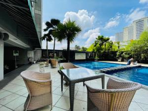 um pátio com uma mesa e cadeiras ao lado de uma piscina em Pretty Room Studio Apartment at Galeri Ciumbuleuit 1st Tower em Bandung