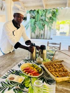a chef is standing at a table with food at Dream Luxury B&b Watamu in Watamu
