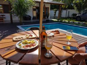 una mesa con comida y bebida junto a una piscina en Casa Harmonia, com 5 suítes em Trancoso-BA en Trancoso