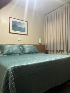 a bedroom with a bed with a green comforter at Apto setor central 808 in Goiânia