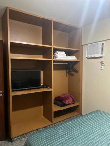 a room with a bed and a tv and shelves at Apto setor central 808 in Goiânia