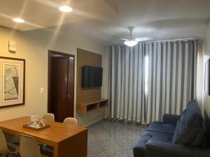 a living room with a blue couch and a table at Apto setor central 808 in Goiânia