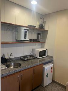 a kitchen with a sink and a microwave on a counter at Apto setor central 808 in Goiânia