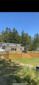 une maison avec une clôture en bois dans un champ dans l'établissement Stuga på ö / närhet till vatten, à Mariestad