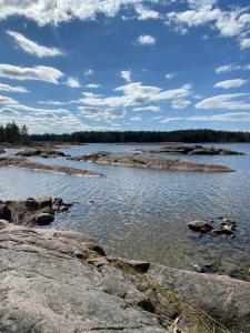 a large body of water with rocks and trees at Stuga på ö / närhet till vatten in Mariestad