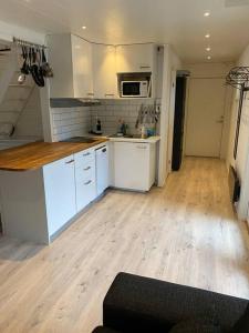 a kitchen with white cabinets and a wooden floor at Stuga på ö / närhet till vatten in Mariestad