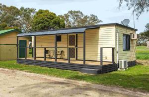 a large wooden house with a porch on the grass at Penola Coonawarra Caravan Park in Penola