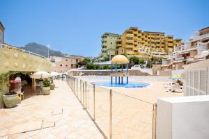 a balcony with a pool with umbrellas and buildings at Great Ocean View Torviscas Beach Home by LoveTenerife in Adeje