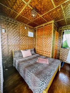 1 dormitorio con 1 cama en una pared de madera en Almare Guest House Siquijor en San Juan