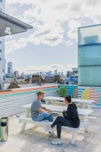 dos personas sentadas en bancos en la parte superior de un edificio en The Social Hotel, Sydney, en Sídney
