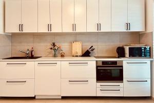 a white kitchen with white cabinets and a microwave at Guestroom Hannover Messe in Hannover
