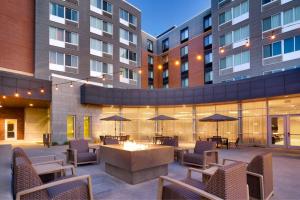 un patio al aire libre con mesas, sillas y sombrillas en Courtyard Lincoln Downtown en Lincoln