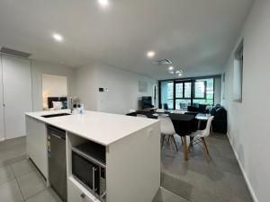 Il dispose d'une cuisine ouverte et d'un salon avec une table et des chaises. dans l'établissement Embark Luxe 2BR 2Bath Apartment in Lynham 1 Secure Carpark Wifi Canberra, à Canberra