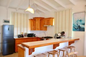 a kitchen with wooden cabinets and a black refrigerator at Blue Whale Villa - Penthouse in Calibishie