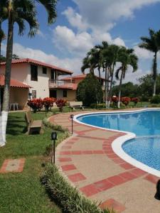 una piscina frente a una casa con palmeras en cabaña completa en la mejor ubicacion del Quindio en Pueblo Tapao