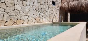 a swimming pool in front of a stone wall at Kin Tulum House downtown in Tulum