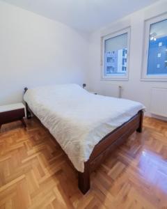 un grande letto in una camera con pavimento in legno di City Center Family Apartment Novi Sad a Novi Sad