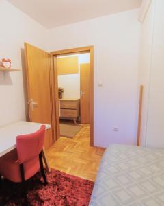 a bedroom with a bed and a table and a chair at City Center Family Apartment Novi Sad in Novi Sad