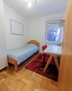 a room with a bed and a desk and a table at City Center Family Apartment Novi Sad in Novi Sad