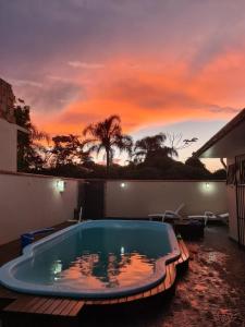 a swimming pool with a sunset in the background at Bela casa, com internet, piscina e churrasqueira para descansar e desfrutar, dias de paz in Barra Velha