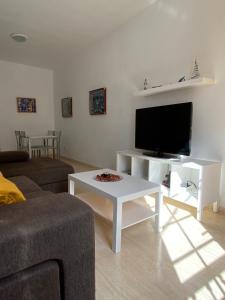 a living room with a couch and a tv and a table at Casa Estribor, vacaciones en ambiente familiar in Punta de Mujeres