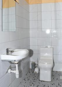 a white bathroom with a sink and a toilet at Intellicents Apartments in Kisumu