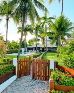 a gate leading to a resort with palm trees at Linda Casa na Penha ! in Vera Cruz de Itaparica