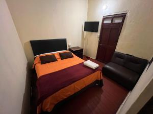 een slaapkamer met een bed en een zwarte stoel bij Orkkowasi backpackers in Arequipa